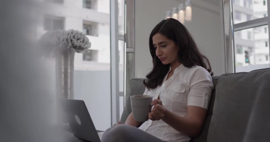 A woman sipping tea while sitting on a couch