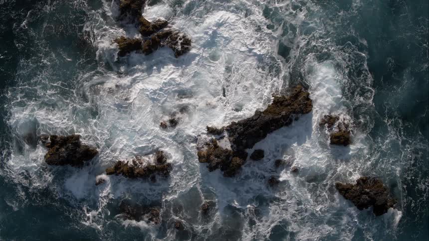 The ocean churns and foams on rocks