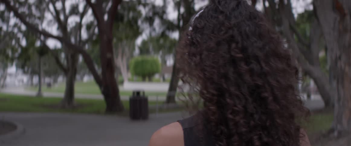 Woman with headphones on walking down a sidewalk