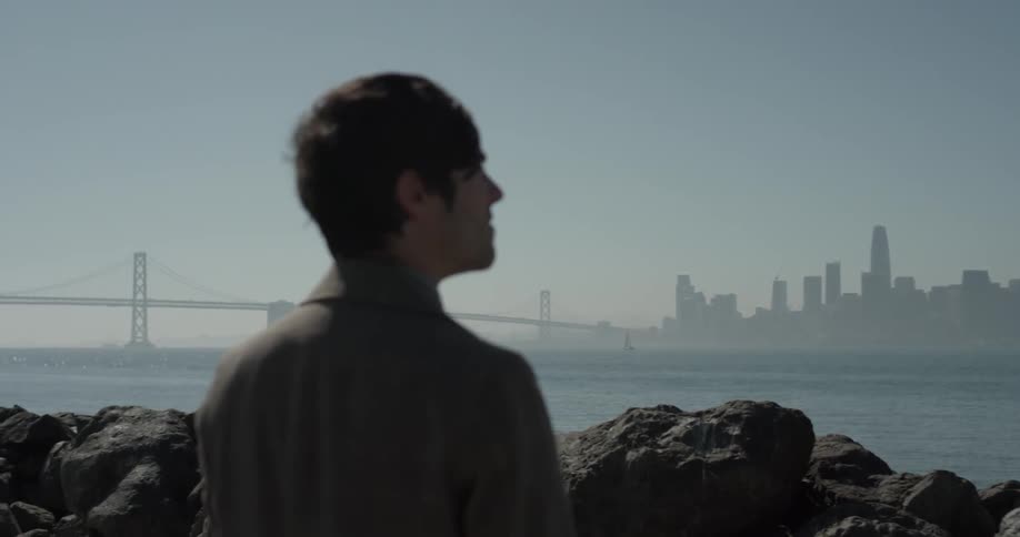 A man looking at a city across some water