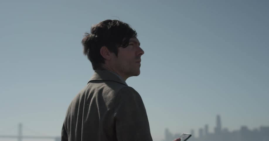 Man looks out in distance while holding a cell phone