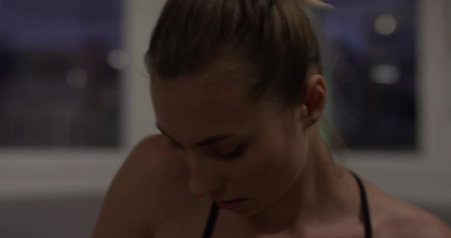 A woman looks down as she stretches