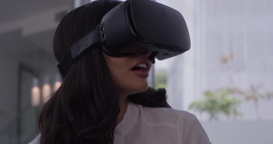A woman puts on some virtual reality goggles and is shocked by the virtual world she sees