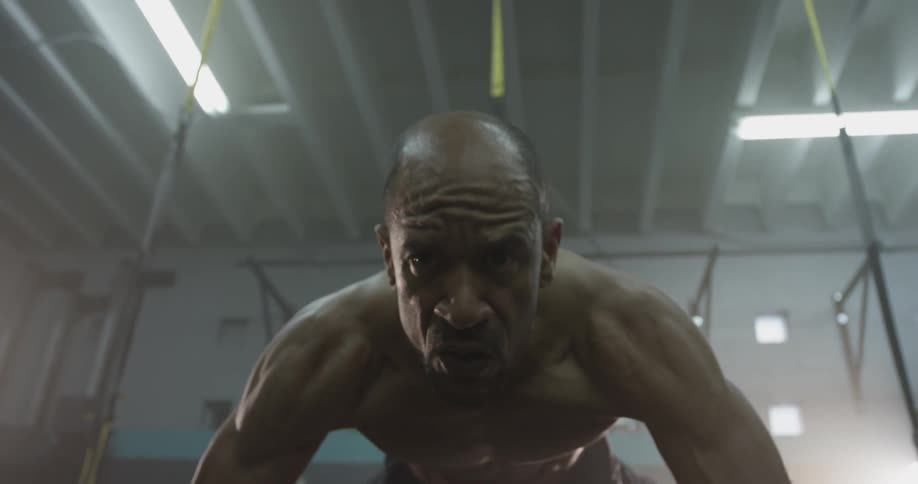 A shirtless man works out with a trx strap