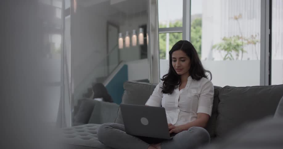 A woman sitting on a couch with a laptop
