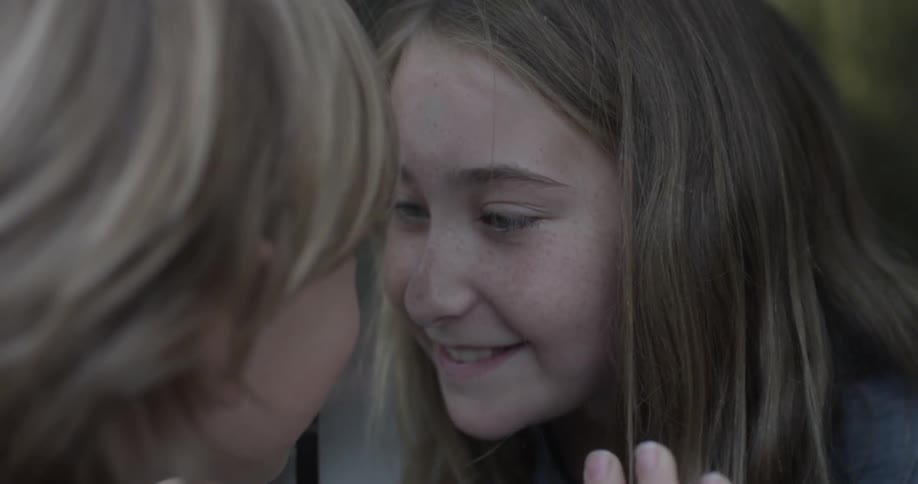 Two children smile at each other from opposite sides of a window