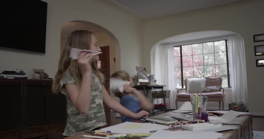 Two child make paper airplanes and throw them