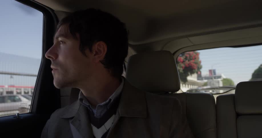 Man rides in backseat of car and looks out window