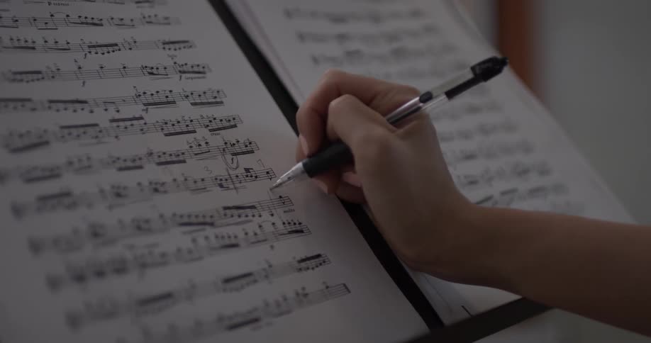 A person writing on a piece of sheet music