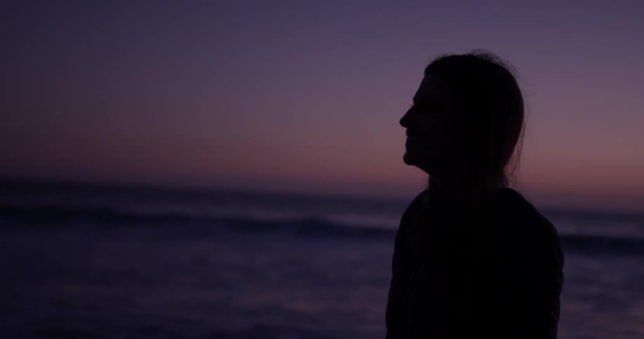 Woman walking near the sea at dusk