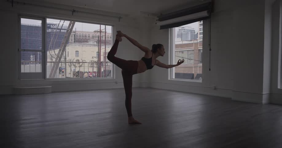 A woman is doing yoga in an empty room