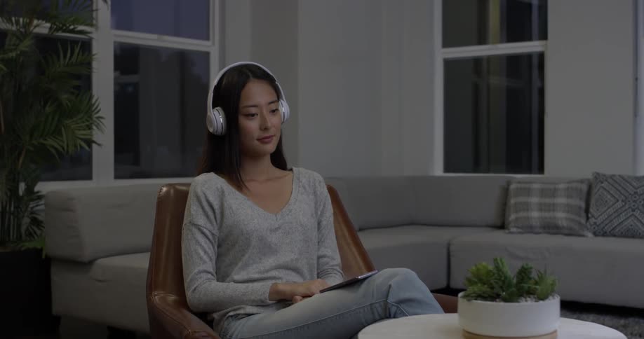 Woman sitting in a house listening to music with headphones