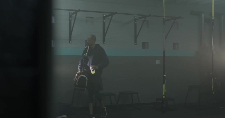 A man is grabbing his gym bag and walking
