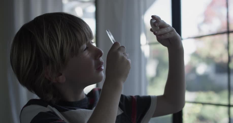 A child is looking through a magnifying glass at a glass oval object