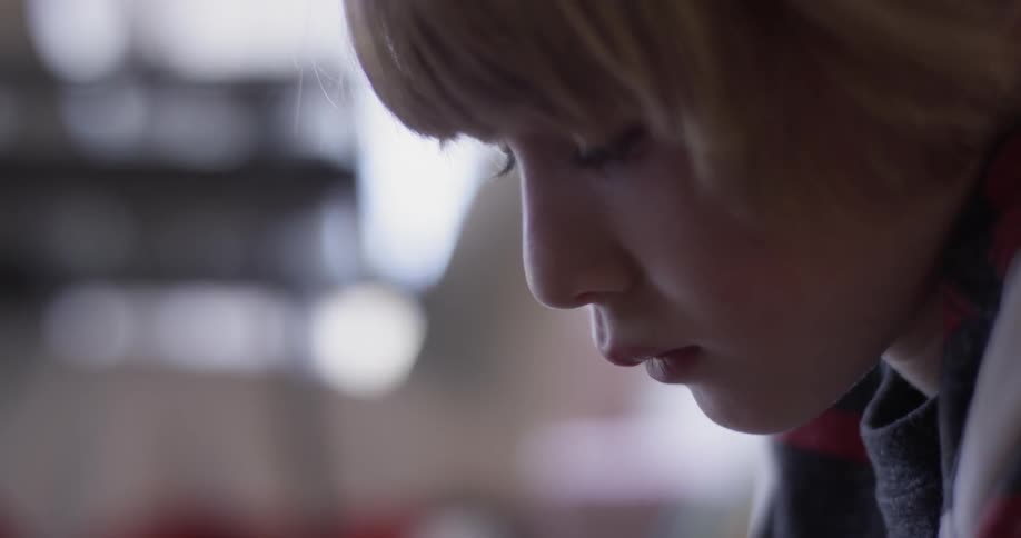 A child looks intently at something he is working on indoors