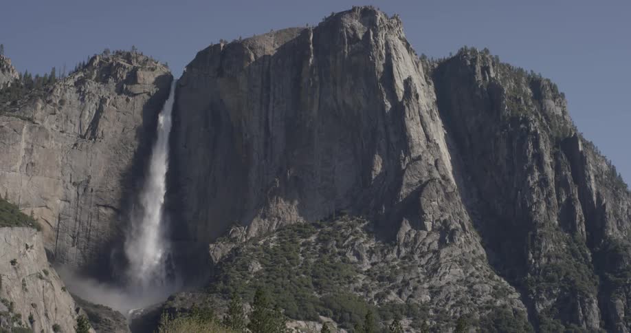 Water falls over waterfall on mountain in the sunshine