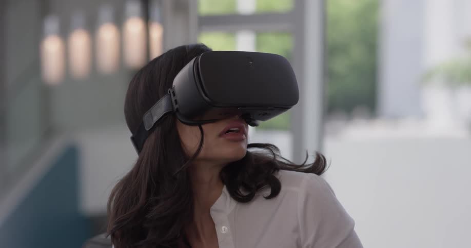 A woman is wearing virtual reality glasses and is afraid or fearful of the things she is seeing in the vr world