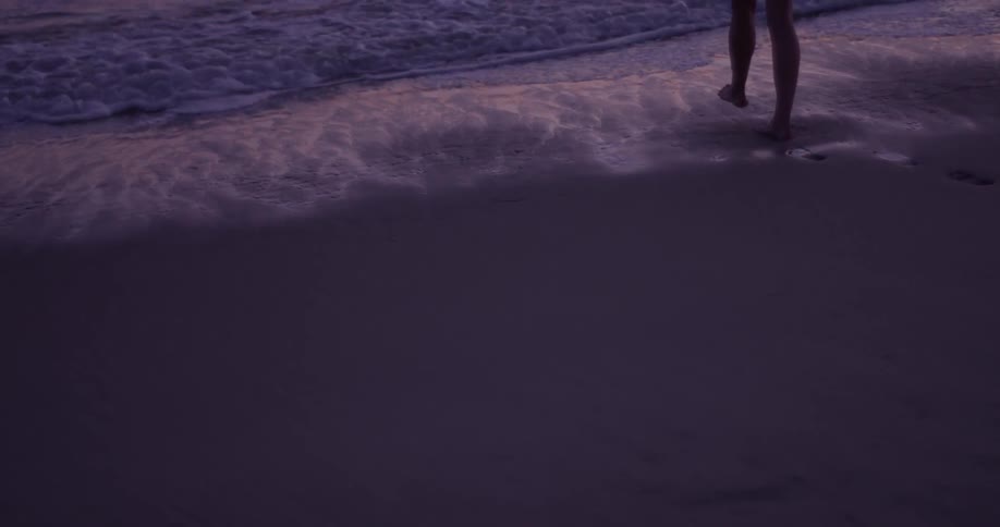 Person walks on the beach at sunset