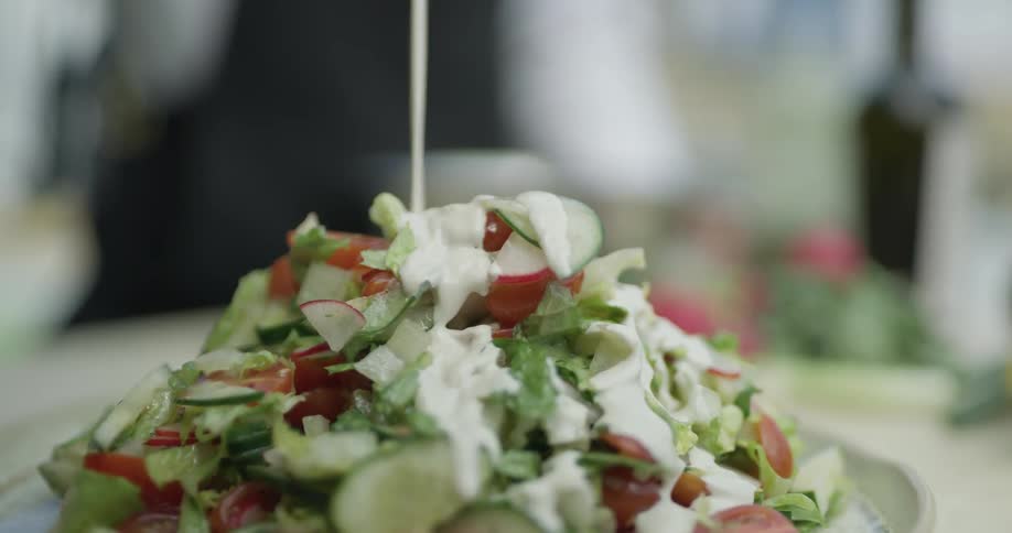 Salad dressing is poured on a salad