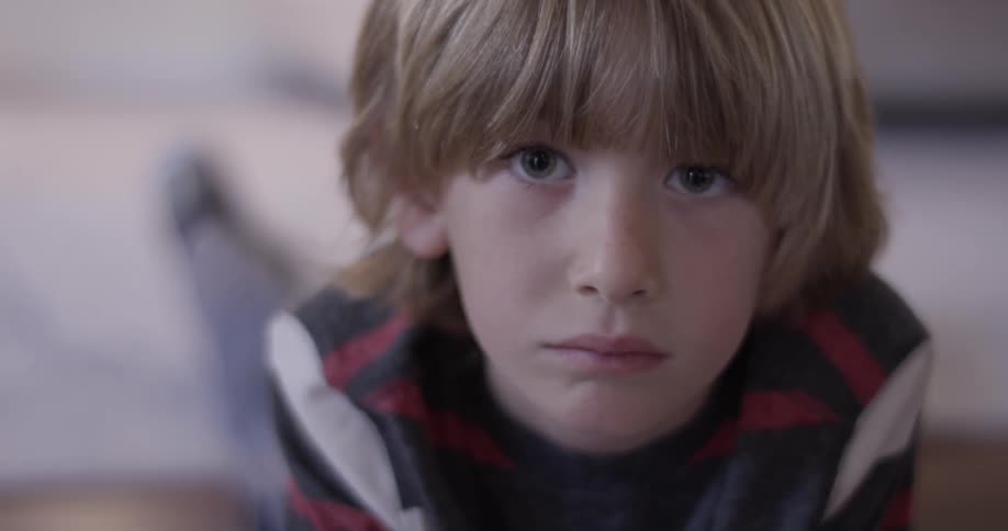 A young boy laying on the ground staring into the camera