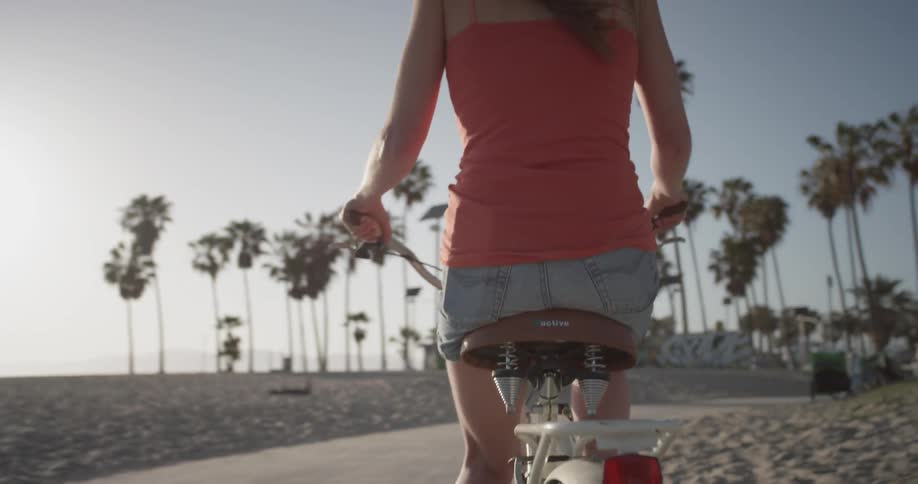 Woman pedals her bike near the beach on a sunny day