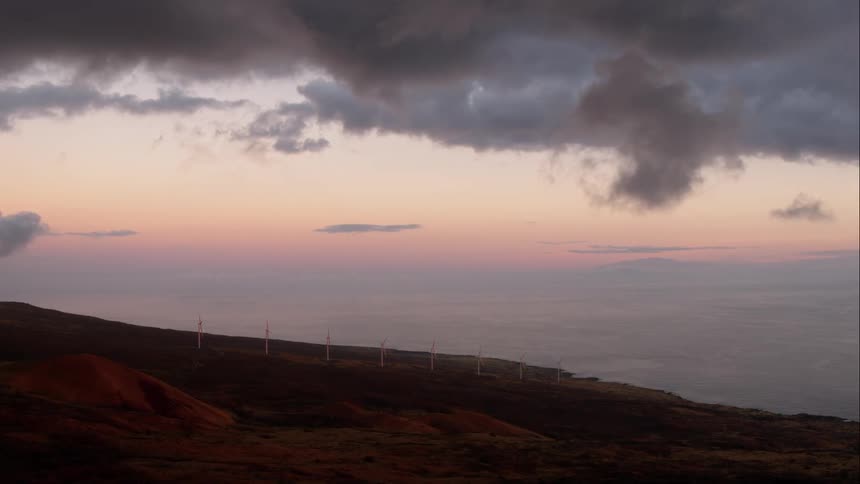 Windmills on a hill next to the ocean