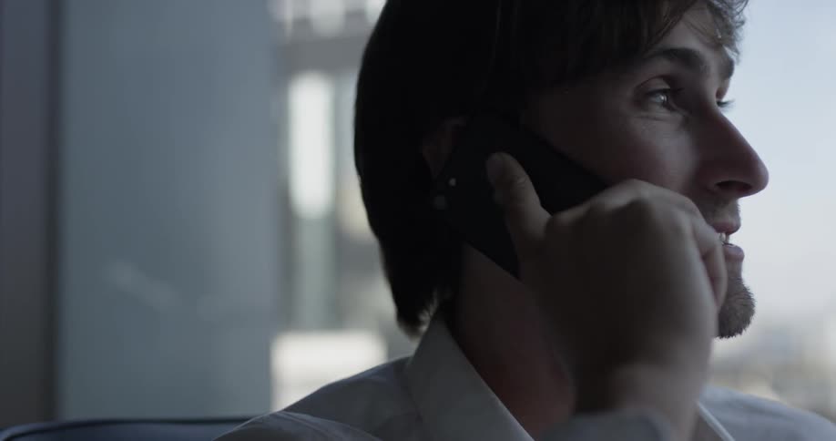 A man standing by the window talking on the phone