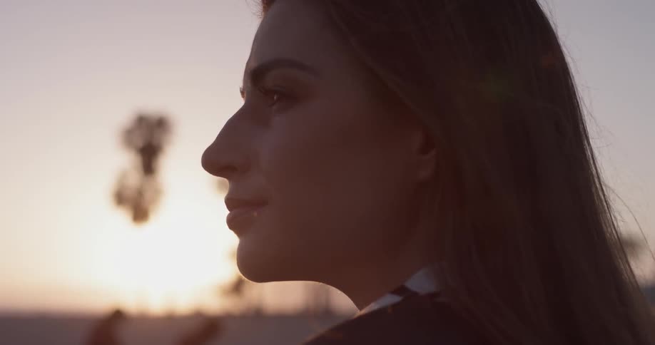 A woman is standing outside at sunset