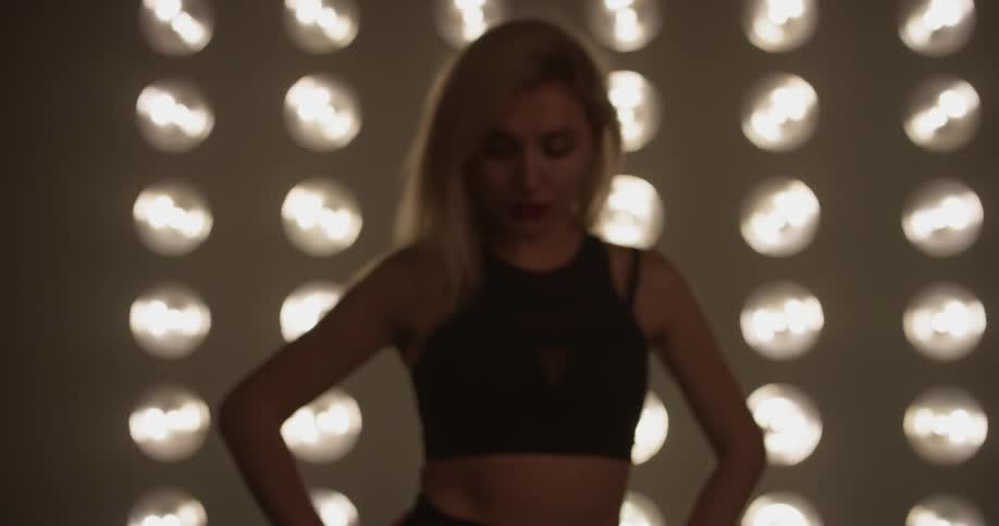 Woman stands in front of a wall with rows of lights in it