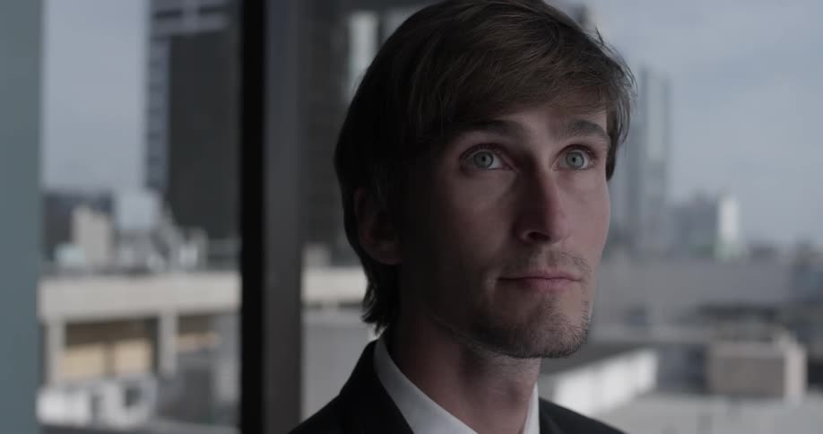 A business man looks around before finally looking up at something
