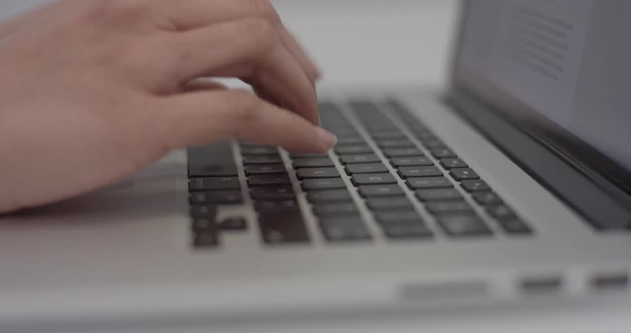 A person typing on a laptop keyboard