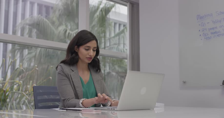 A woman typing on a laptop in a white office