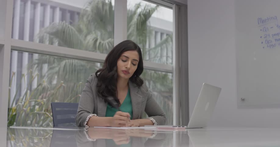 Woman sitting at a desk in an office with a laptop and paper