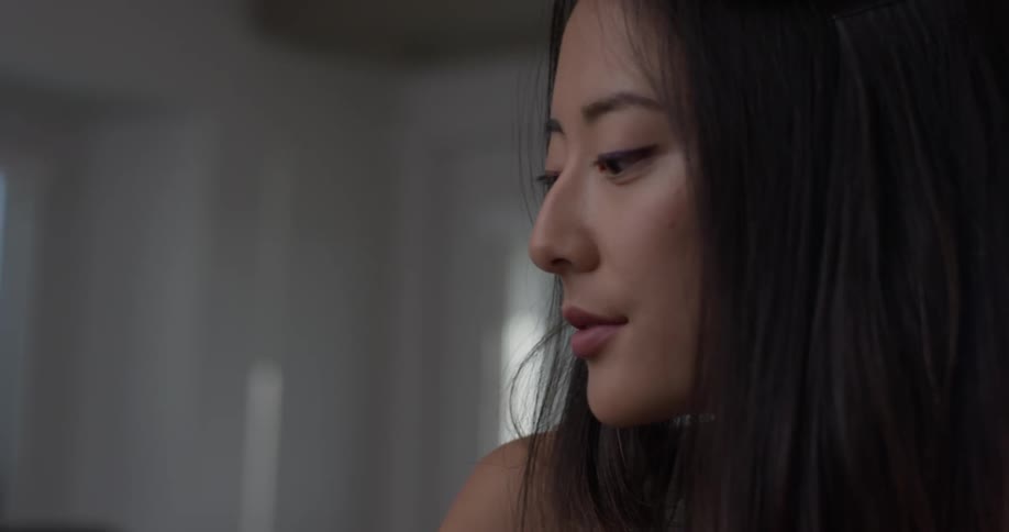 Woman sits in a room smiling and looking down