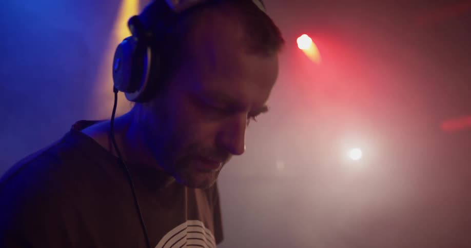 A man is wearing headphones indoors with flashing lights