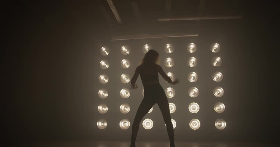 Woman dances in front of a large wall of lights