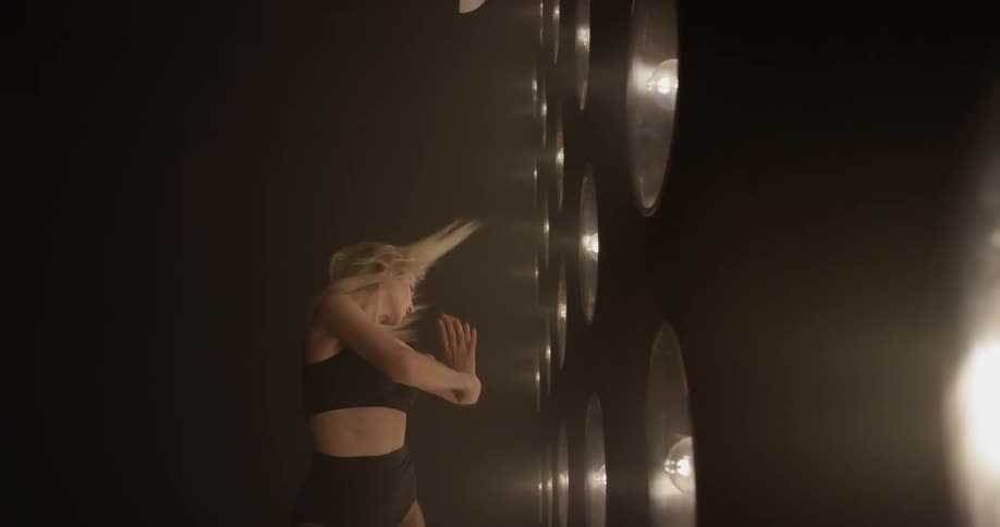 Woman dances in front of a large wall of lights