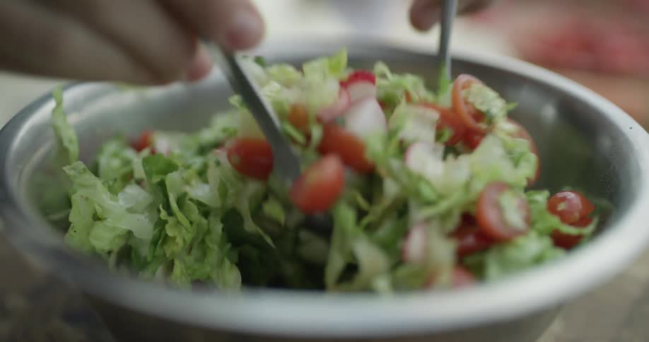 A person using two spoons to mix a chop salad