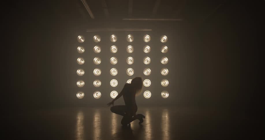 A woman dancing on a stage with a lot of lights on
