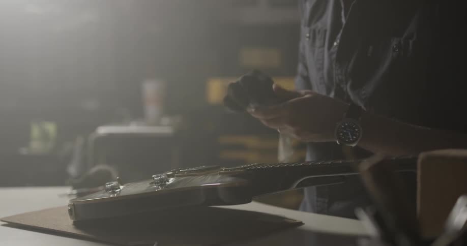 Man polishes guitar with cloth