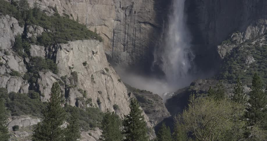 Many trees on top of mountain hills and a waterfall with water droplets mist and fog