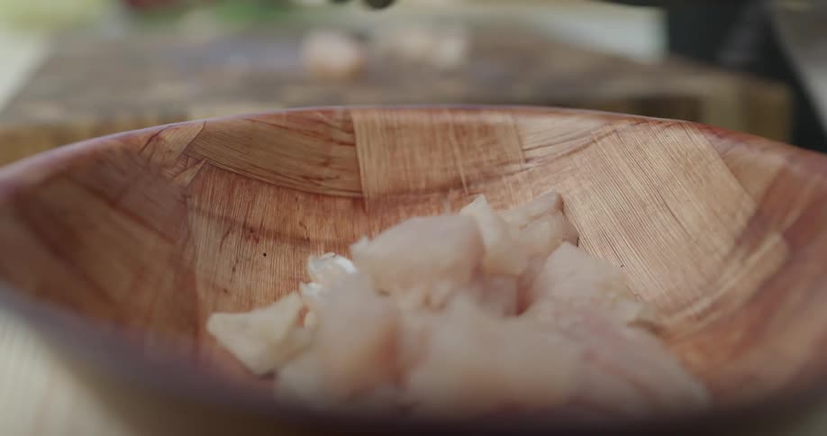 Someone puts ingredients in a wooden bowl
