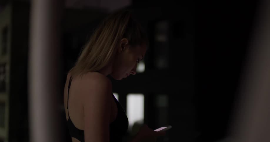 A woman looks at her phone and then away from it and chuckles