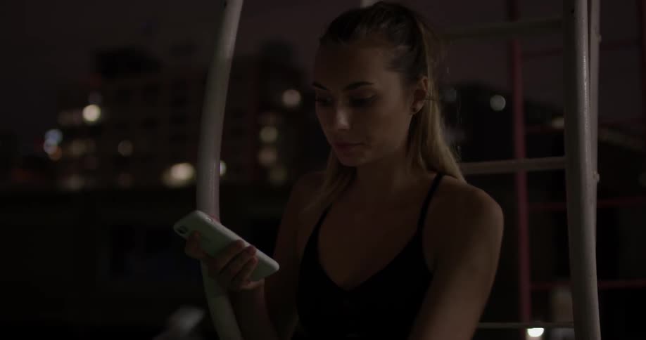 A woman looking at a cell phone at night