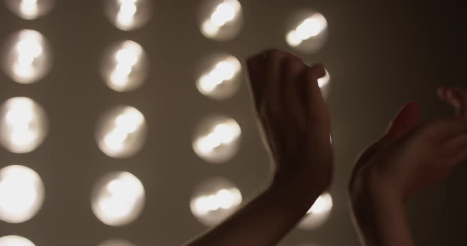 Woman waves her arms in front of rows of lights
