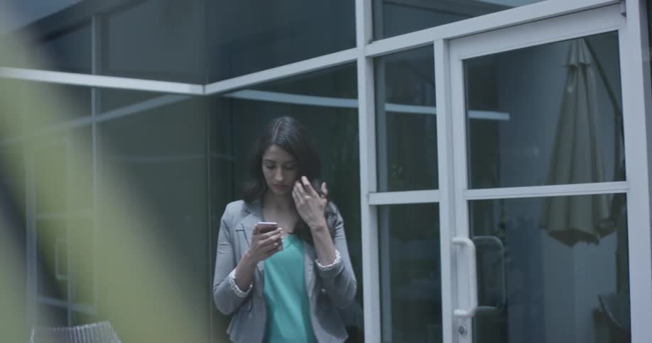 A woman looks at her phone and scratches her face