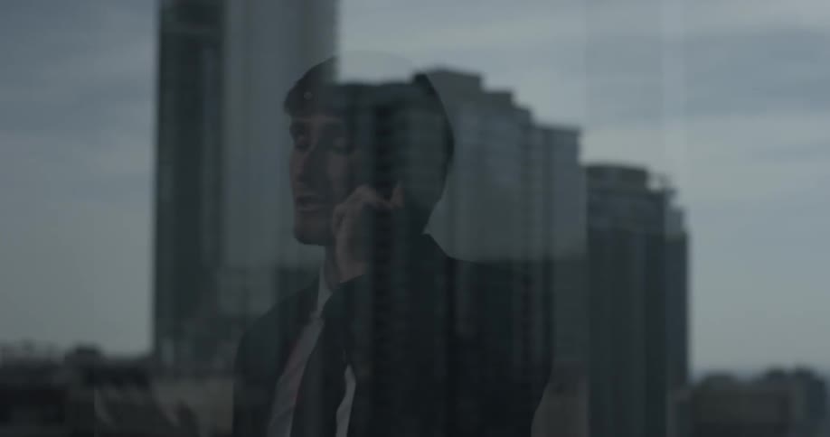 Business man looks out a window while talking on the phone