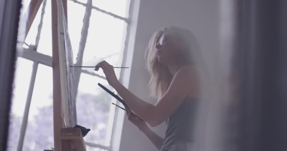 A woman standing in front of an easel painting