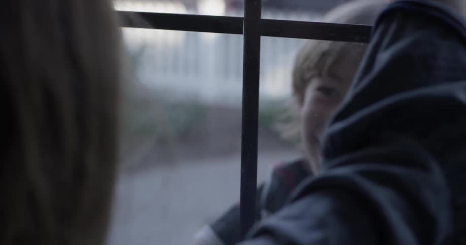 A child runs to a window and presses his hands to it