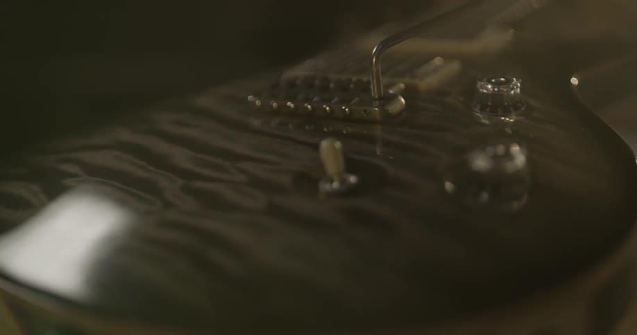 An electric guitar is shown in a small light in a dark room